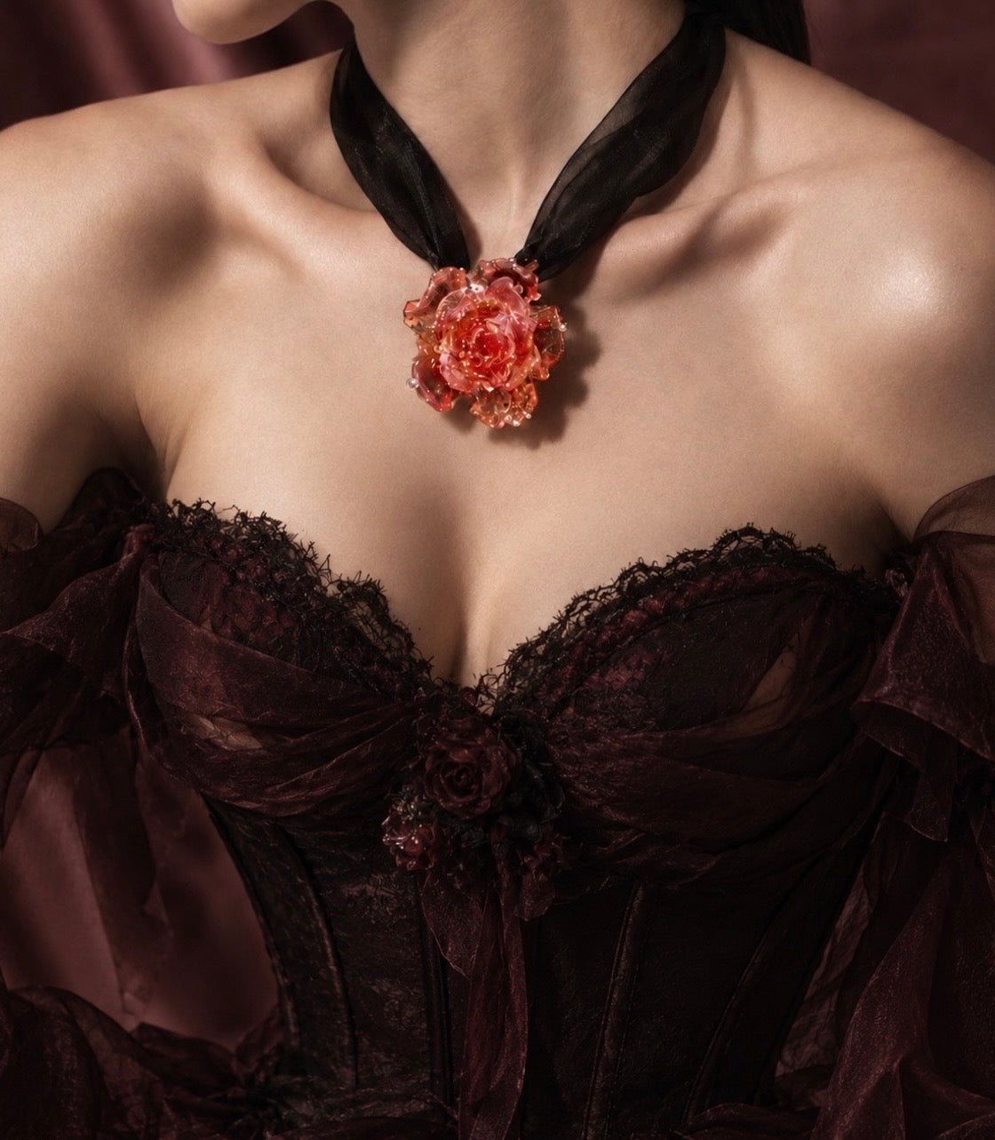Model wearing REALONETARA’s Magic Rose necklace, featuring a translucent red Liuli rose on black organza, styled with a dark lace corset dress.