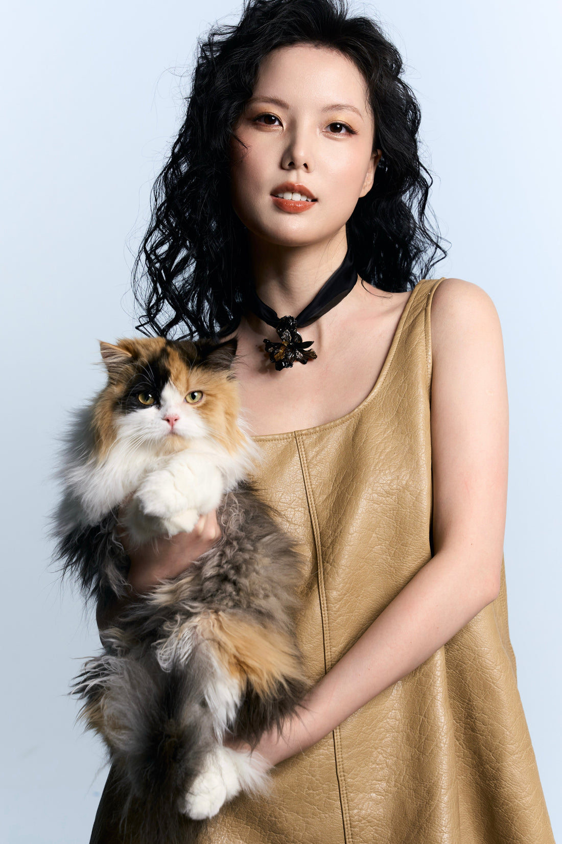 Founder wearing REALONETARA Starfire Black Gold Liuli Iris Choker Necklace with a camel leather sleeveless dress, holding her calico cat