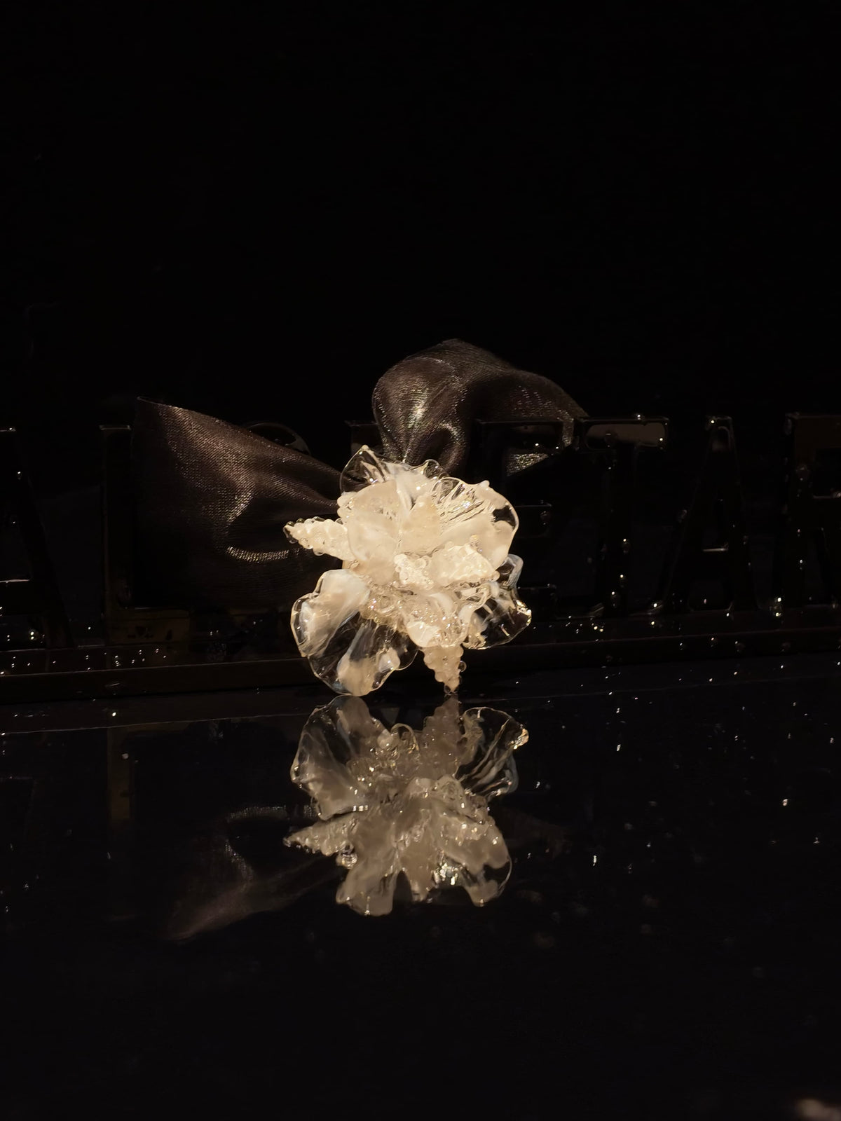 Close-up of handcrafted white Liuli glass iris floral pendant, pristine white petals with crystal clear details against black background