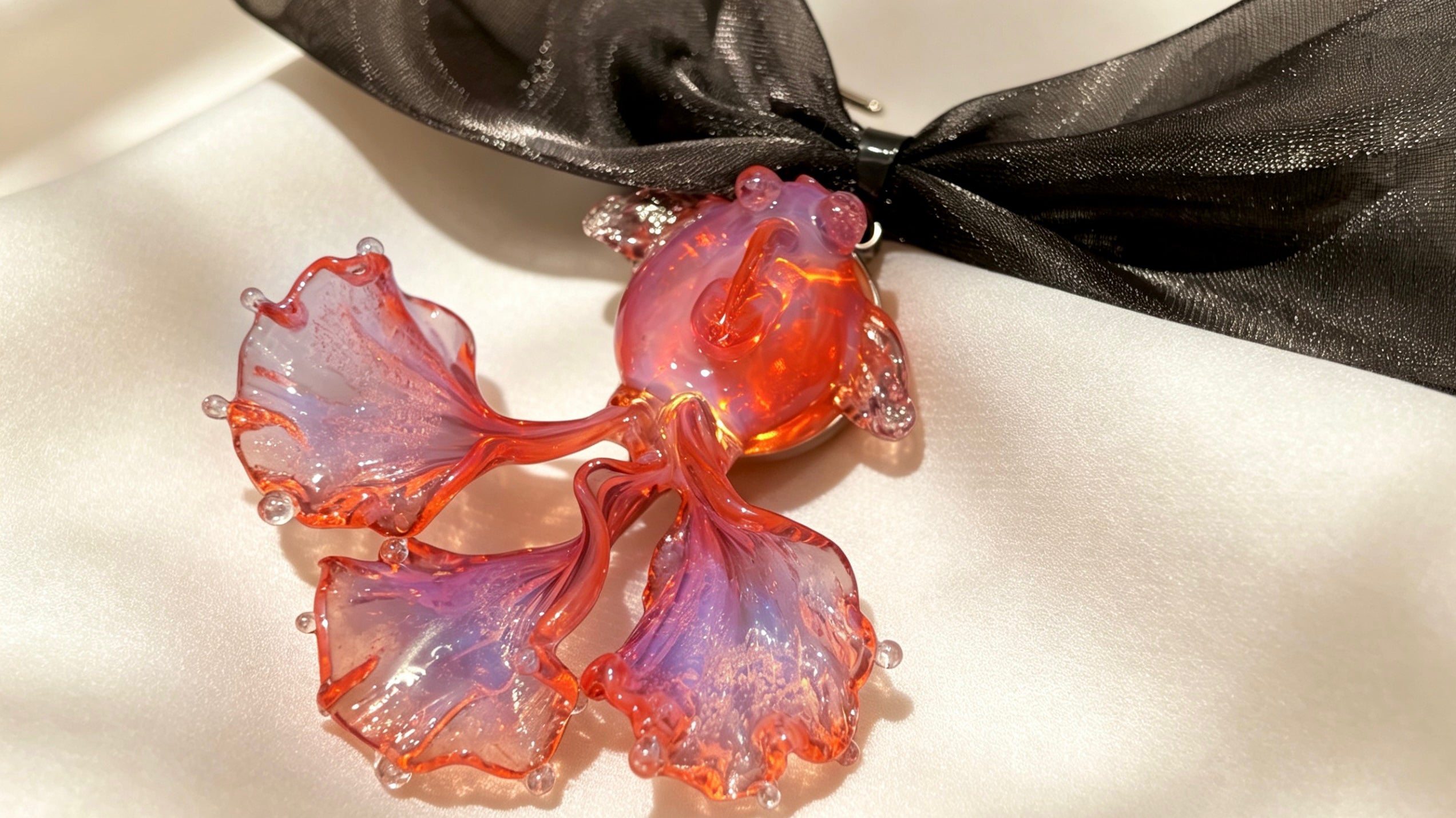 Handcrafted Liuli koi fish necklace in pink and blue, displayed on an ivory white background, front view.