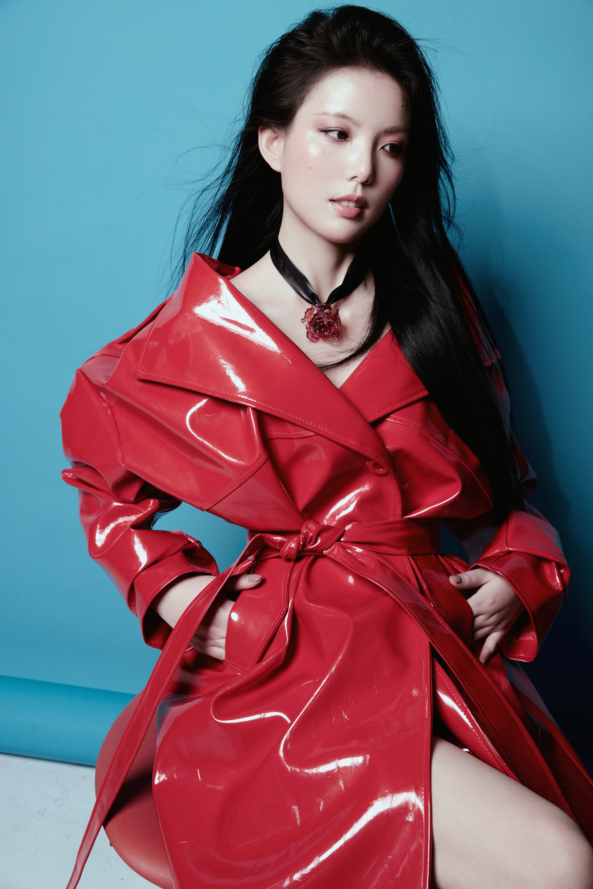 Model in red leather jacket wearing Magical Red Black Liuli Glass Rose Choker Necklace, black hair, hands in pockets, gazing to the side against solid blue background